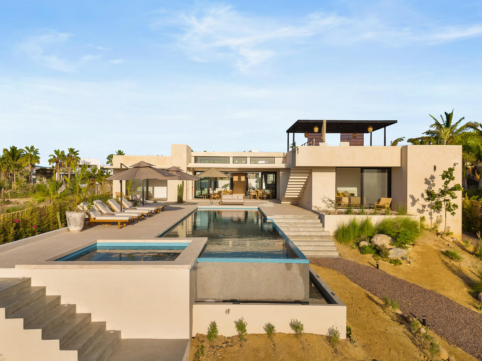 Los Cabos Luxury Las Tunas The Nacuii Residence is a refined luxury home crafted to exceed the expectations of even the most discerning buyer. Nestled on a generous and private 3,000 m² lot (0.73 acres), it's just a short, effortless stroll to the untouched, sandy shores of Las Tunas — perfect for enjoying the serene coastal landscape and dramatic sunsets. The home offers a thoughtful layout with 3 spacious bedrooms, a separate studio, a cozy TV lounge, and 6 full bathrooms, including two principal suites, a guest room, a detached studio, and a dedicated media or family room. Expansive sliding glass doors invite natural light throughout the interiors while showcasing tranquil garden for sale